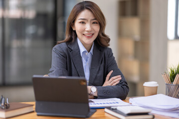 Fototapeta premium Asian Business woman using calculator and laptop for doing math finance on an office desk, tax, report, accounting, statistics, and analytical research concept 