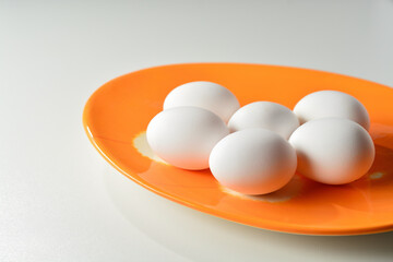 Fresh white eggs on an orage plate. White background.