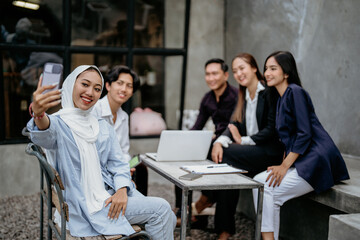 Portrait of a group of businesspeople taking a selfie together with mobile phones during an outdoor meeting