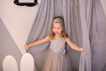 little girl playing with curtains in her room