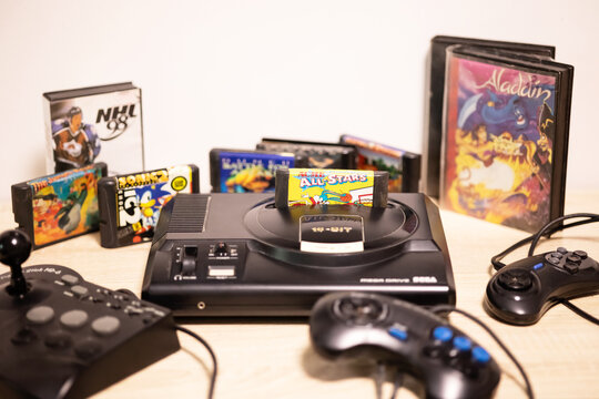 Sevastopol, Russia: July 11, 2023: retro game console with a cartridge inside on the background of cartridges NHL, Aladdin, Sonic 2. Sega mega drive and gamepad and fighter stick MD 6 for the left 