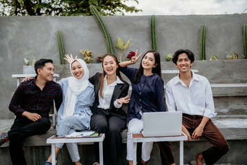 group of young businesspeople excited for cooperation while sitting together at an outdoor gathering