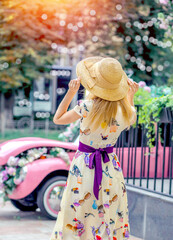 Tourist blond girl in a summer elegant dress and hat, view from the back. Travel concept.