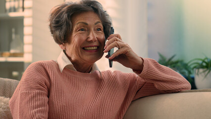 Happy Caucasian old woman carefree middle aged senior lady cheerful smiling retired grandma elderly female granny grandmother talking on smartphone mobile phone talk sharing news on cellphone at home