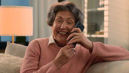 Happy laughing talking phone Caucasian old woman carefree senior lady listening funny news smile laugh retired grandma elderly female grandmother mobile conversation smartphone communication at home