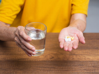 Senior woman holding a glass of water and medicines.