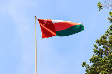 Flag of Oman flutters in the wind on the roof of the fortress;