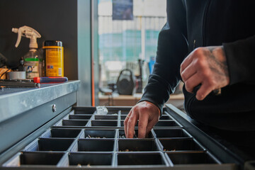 Close up view of the male bicycle mechanic taking details from box while repairing bicycles