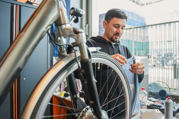 Fototapeta na wymiar Young caucasian repairman guy repairing bike in modern workshop