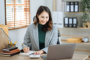 Business woman take notes and use the calculator with calculations about the expenses at the office.
