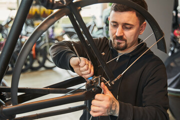 Serious caucasian male worker repairing bicycle wheel