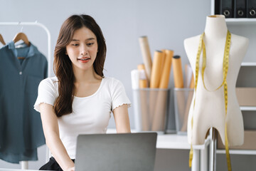Female fashion designers use smart phones and use laptops with digital tablet computers to get orders from customers.
