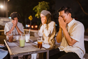 young Asian Muslims pray to God before eating Ramadan dinner at an outdoor cafe