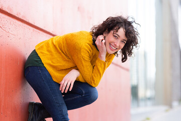 Attractive woman bending over and smiling by a wall