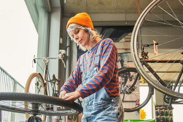 Calm woman cycling mechanic checking bicycle wheel spoke in workshop
