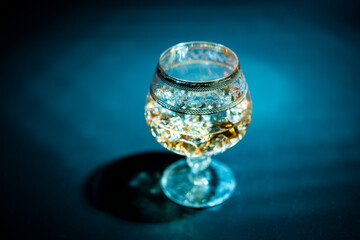 Glass with cognac and ice on a dark background. the concept of alcoholism and drinking