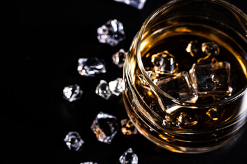 Glass with cognac and ice on a dark background. the concept of alcoholism and drinking
