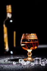 Glass with cognac and ice on a dark background. the concept of alcoholism and drinking