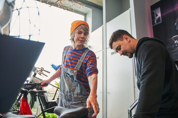 Attentive colleagues communicating while repairing bicycle in workshop