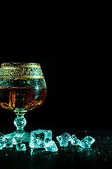 Glass with cognac and ice on a dark background. the concept of alcoholism and drinking