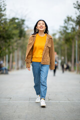 Fototapeta premium Full body smiling young asian woman walking