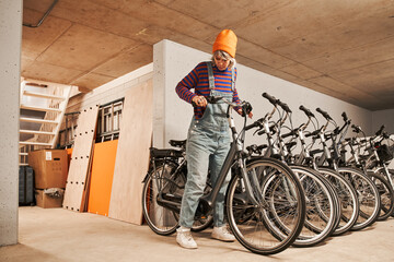 Full length view of the focused woman checking bike while preparing repairing it