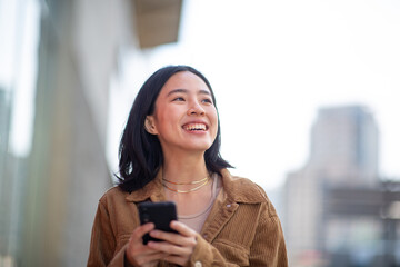 smiling young woman using phone in city