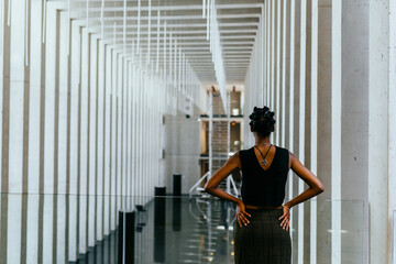 Rear vew of slim pretty african woman spending time in modern interior of art gallery center.