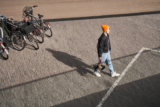 High Angle View Of The Positive Woman Carrying Roller Skates And Walking