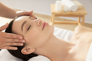 Young woman on face massage, masseur hands on light background