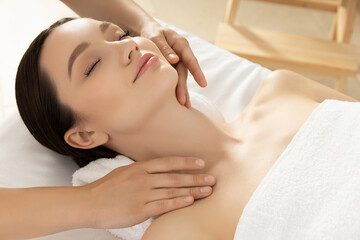 Young woman on face massage, masseur hands on light background