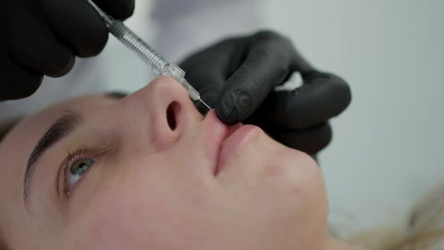A cosmetologist performs a lip augmentation procedure in the salon.