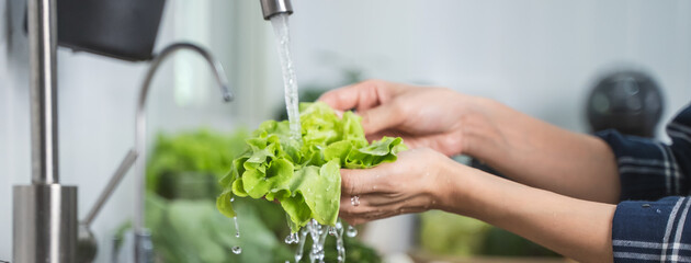 Close up of hands people washing vegetables by tap water at the sink in the kitchen to clean ingredient prepare a fresh salad.