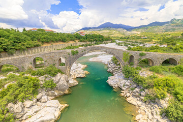Fototapeta na wymiar Mesi Bridge in Albania is stunning architectural wonder that spans Kir River in a quaint village. This historic stone bridge, originating from Ottoman era, brings a sense of heritage to surroundings.