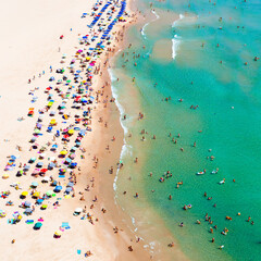 A lot of people on the beach swimming and relaxing om sunny warm day view from above hill high ground with copter