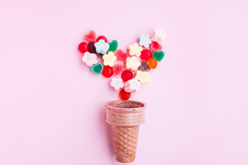 Multicolored Marshmallows and jelly candy out of ice cream cone on pink background, Flower Shaped Marshmallows and jelly candy heart shaped