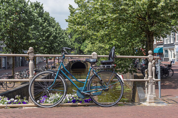 Bicycles are leaning against a fence on a bridge over a river in Leeuwarden, Netherlands