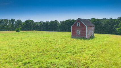 Old small abandoned house in the middle of a field in the Canadian countryside in Quebec