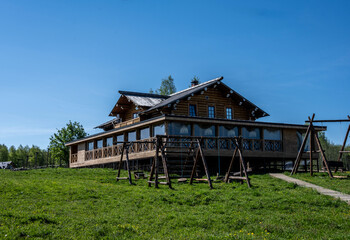 Fototapeta na wymiar a large wooden house on a hill in a green meadow against a blue sky