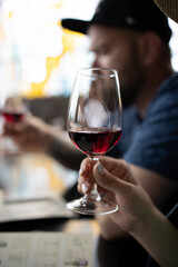 Close-up of a woman's hand with a glass of pink champagne, selective focus. Tourist tour: wine or champagne tasting. Winemaking, oenology, champagne production