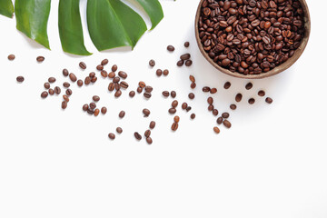 Roasted coffee beans in a coconut bowl and monstera leaf on a white background. Top view, flat lay. Eco concept of coffee beans. Copy space. Green natural technologies