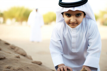 Selective focus on Arab boy wearing kandura playing with father at a park. Young Emirati UAE National son with his parent spending time together outdoors.
