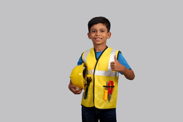 Future architect Indian Boy wearing construction manager uniform and helmet showing thumbs up 