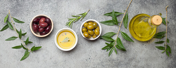Fototapeta na wymiar Composition with green and brown olives, extra virgin olive oil in glass bottle, olive tree branches on gray concrete stone rustic background overhead, Mediterranean concept