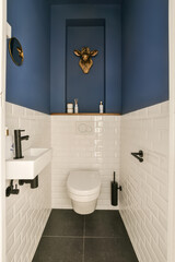 a small bathroom with blue walls and white tiles on the walls there is a toilet in front of the sink