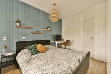 a bedroom with wood flooring and blue wallpapers on the walls, bed is made up in black velvet