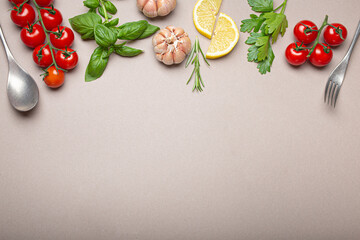 Naklejka na ściany i meble Composition with branch of fresh cherry tomatoes, herbs, garlic cloves, lemon wedges, kitchen spoon and fork on minimalistic gray clean background, overhead shot with copy space