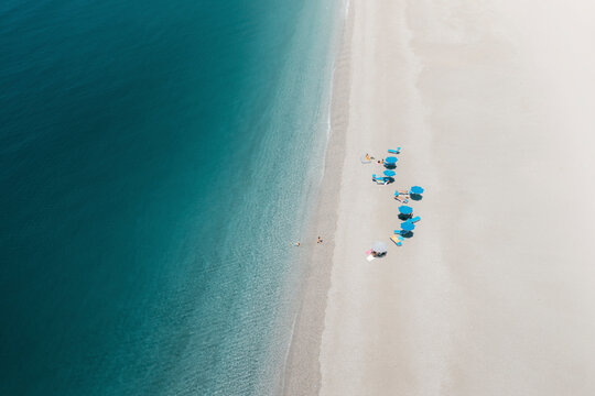 Aerial view of people with blue umbrellas in Baia del Tono, Milazzo, Sicily.