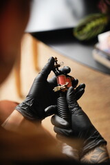 Close-up of a gloved hand holding a small vintage tattoo machine, perfect for tattoo-related themes and visual projects. 