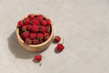 Raspberries in a wooden cup on a gray background. Macro